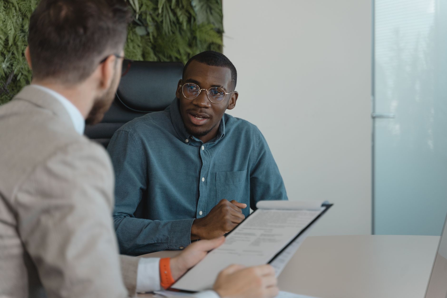 Deux hommes en pleine discussion dans un bureau autour d’un document.